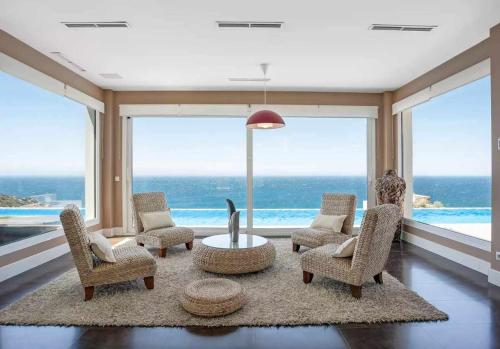 a living room with chairs and a table and a large window at LUJOSA VILLA PISCINA 25 METROS SUIT 60m2 SPA SAUNA in Zahara de los Atunes