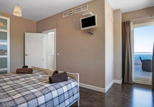 a bedroom with a bed and a tv on the wall at LUJOSA VILLA PISCINA 25 METROS SUIT 60m2 SPA SAUNA in Zahara de los Atunes