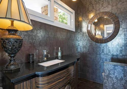 uma casa de banho com um lavatório, um candeeiro e um espelho em LUJOSAVILLA PISCINA 25 METROS SUIT 60m2 SPA SAUNA em Zahara de los Atunes