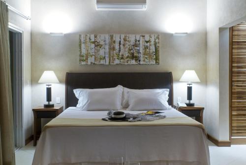 a bedroom with a bed with two lamps and a plate on it at Abayomi Hotel in Ilhabela