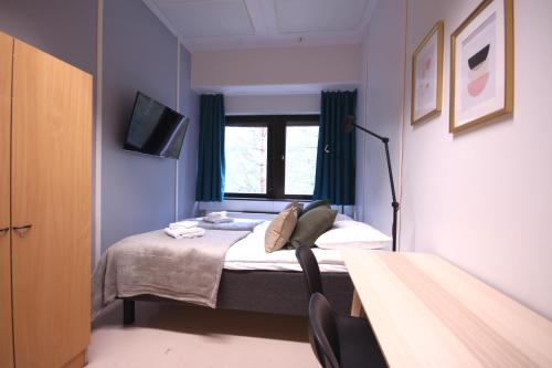 a small room with a bed and a window at Forenom Hostel Espoo Kilo in Espoo