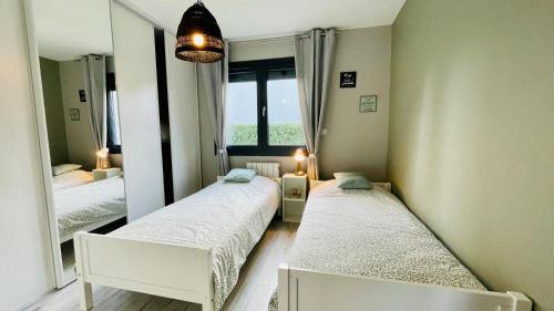 une chambre avec deux lits et un grand miroir dans l'établissement Au Grand Air - Maison de vacances Merlimont plage, à Merlimont
