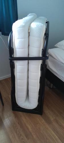 a stack of white towels in a basket next to a bed at FolkiaCenter Gästhem - Vieraskoti - Guesthouse in Hanko