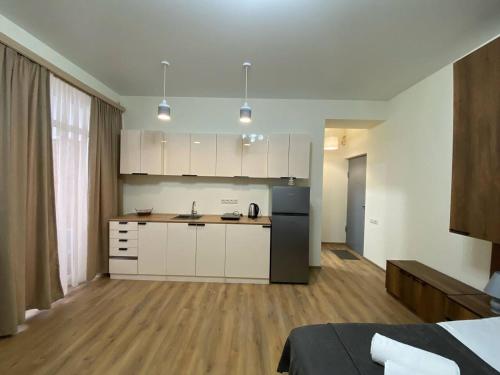 a kitchen with white cabinets and a black refrigerator at Tbilisi cozy appartment in Tbilisi City