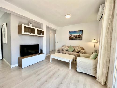 sala de estar con sofá y TV en Apartamento de playa reformado, en Rincón de la Victoria