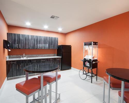 a kitchen with two tables and a refrigerator at MainStay Suites Hobbs in Hobbs