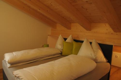un letto con lenzuola bianche e cuscini verdi in una stanza di Haus Lagger a Seefeld in Tirol