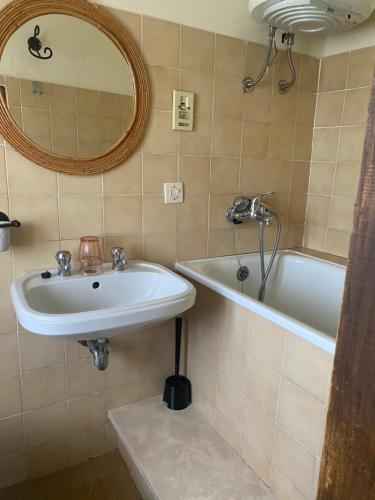 uma casa de banho com um lavatório, uma banheira e um espelho. em Casa Faini em Sorano