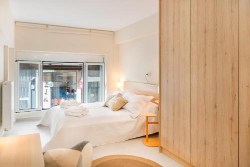 een slaapkamer met een bed en een groot raam bij Praxitelous 141 City Apartment in Piraeus