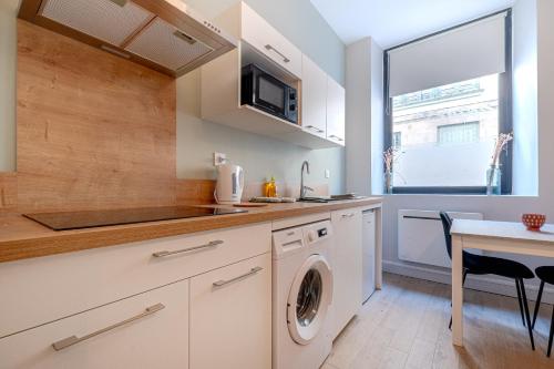 uma cozinha com máquina de lavar e secar roupa ao lado de uma mesa em studio banc léger cœur de ville em Limoges