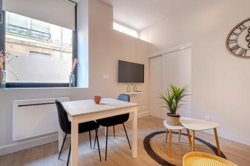 uma sala de jantar com mesa e cadeiras e um relógio em studio banc léger cœur de ville em Limoges