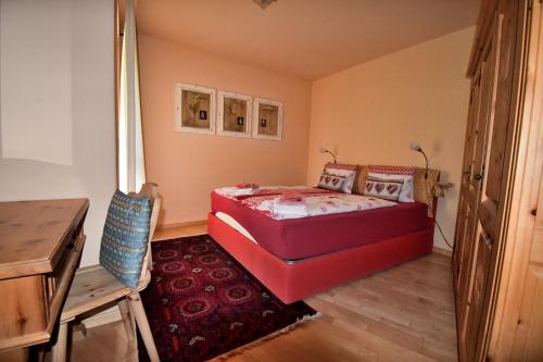 a bedroom with a red bed and a red rug at 3.5 Dmura Fewo Bernina in Samedan