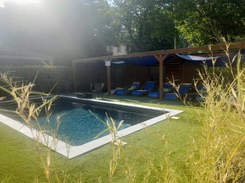 a swimming pool in a yard with blue chairs at Hôtel Les Alizés in Puget-Théniers