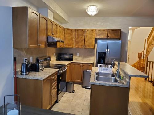 a kitchen with wooden cabinets and stainless steel appliances at RAESABU GUEST HOUSE in Brampton