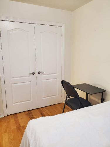 a bedroom with a white bed and a black chair at RAESABU GUEST HOUSE in Brampton