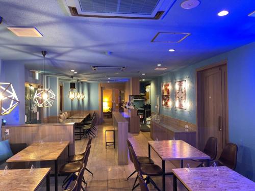 restauracja z drewnianymi stołami i krzesłami oraz niebieskimi światłami w obiekcie Hotel Seagull w mieście Izumisano