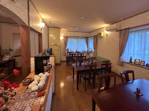 a dining room with tables and chairs and windows at Pension Hinode in Hachimantai