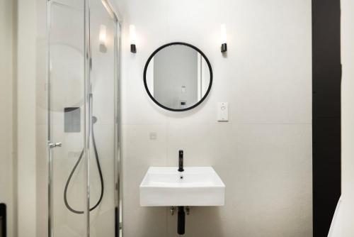 a white bathroom with a sink and a mirror at Modern City Living Studios at Antigallican in London