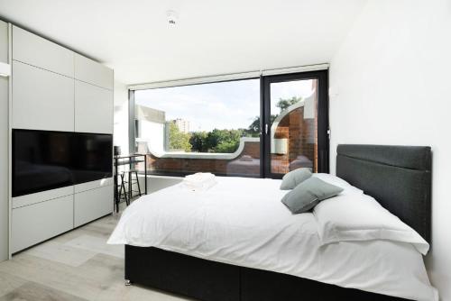 a bedroom with a large bed and a large window at Modern City Living Studios at Antigallican in London