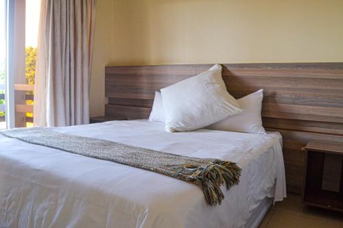 a bedroom with a bed with white sheets and pillows at Ponta View Hotel in Ponta do Ouro