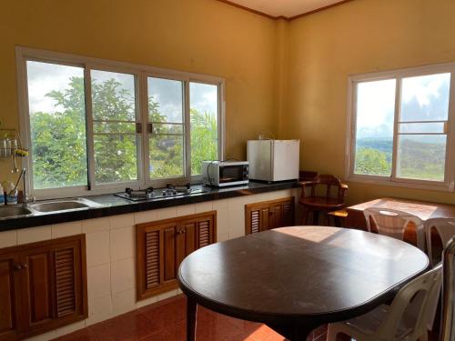 cocina con mesa, fregadero y 2 ventanas en Chaikho Home en Ban Khao Ya Nua