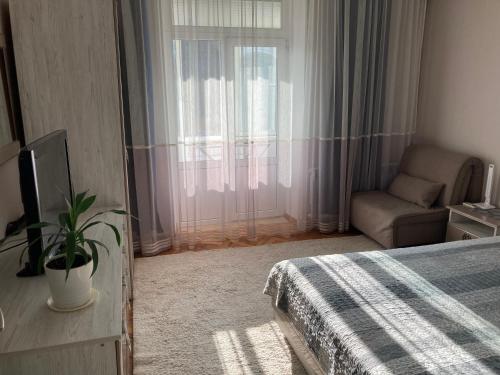 - une chambre avec un lit, une chaise et une fenêtre dans l'établissement Apartment Soborna St., à Vinnytsia