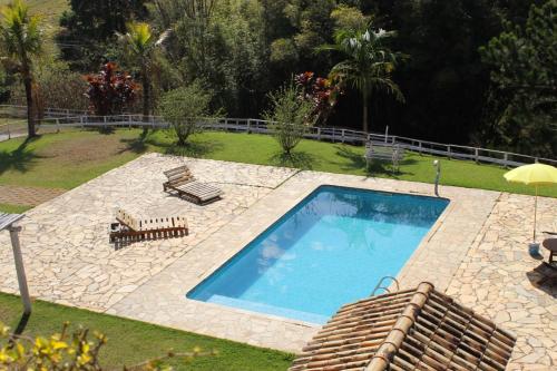 een zwembad met 2 stoelen en een parasol bij Chalé Canto da Seriema in Joanópolis