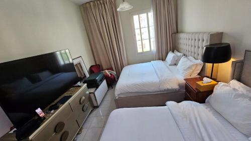 a hotel room with two beds and a flat screen tv at Al Ahmer Apartments in Dubai
