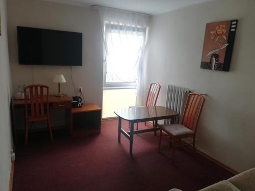 a living room with a table and chairs and a television at Hotel Gromada Łomża in Łomża