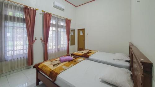 two beds in a bedroom with red curtains at Villa Pakis Residence Banyuwangi in Banyuwangi