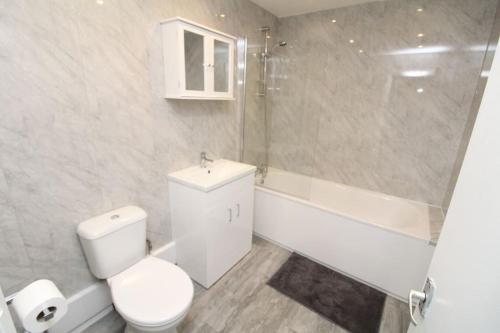 uma casa de banho com um WC, uma banheira e um lavatório. em Modern 2 Bed Close to City em Londres