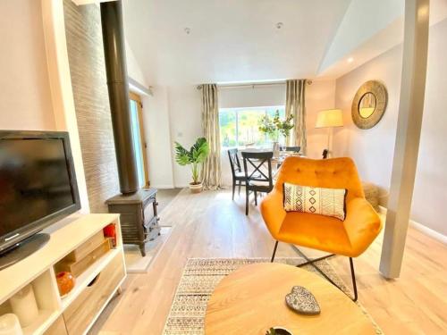 uma sala de estar com uma cadeira laranja e uma televisão em The Waterbaby em Calstock