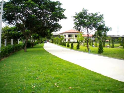 un sendero en un parque con árboles y césped en Sripiamsuk Resort Bangkok en Pathum Thani