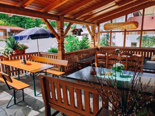 eine Außenterrasse mit Tischen, Stühlen und einem Sonnenschirm in der Unterkunft Gasthof Oberer Wirt in Elisabethszell