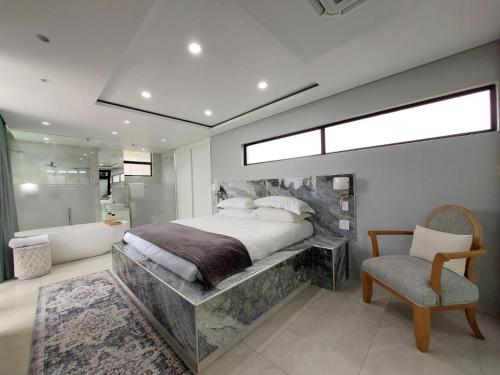 - une chambre avec un grand lit, une baignoire et une chaise dans l'établissement Ntomb'lele Ocean View Luxury Holiday Villas, à Tugela Mouth