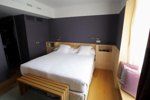 a bedroom with a large white bed and a bench at Hotel Continental Balneario de Panticosa in Panticosa