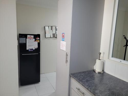 a kitchen with a black refrigerator and a counter at Joondalup Apartment in Perth