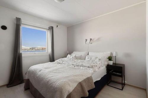 a white bedroom with a large bed and a window at Cozy home. Fantastic view and parking in Tromsø