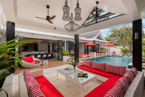 a living room with a red couch and a pool at Villa Mango with staff (brand new) in Amphoe Koh Samui