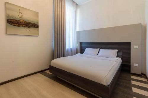 a bedroom with a bed and a painting on the wall at Secret Apartments in Kyiv