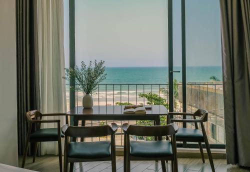 einen Esstisch mit Stühlen und Meerblick in der Unterkunft Anstay Beach Da Nang in Đà Nẵng