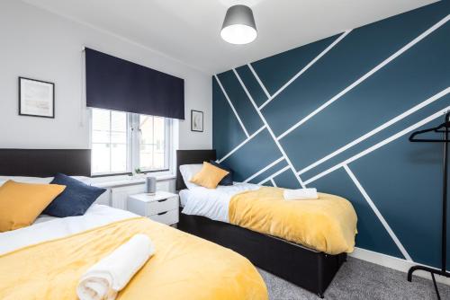 ein Schlafzimmer mit zwei Betten und einer blauen Wand in der Unterkunft 3 Bedroom House Ashford, Kent - Free Parking - Free WiFi - Big Monthly Discounts - Sleeps 5 - Elite Stays UK in Ashford