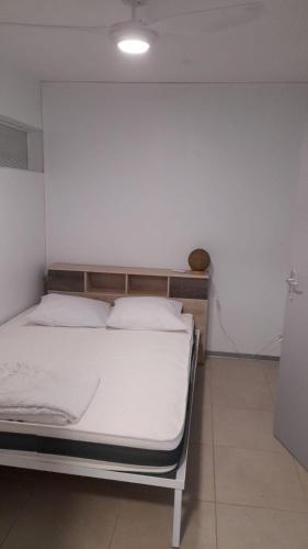 uma cama com lençóis brancos e almofadas num quarto em T2 Bambou em Fort-de-France