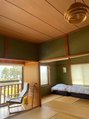 熊野市にあるアタシカデイズ Kumano Kodo Private Beach Houseのベッドルーム(ベッド1台、椅子1脚、バルコニー付)