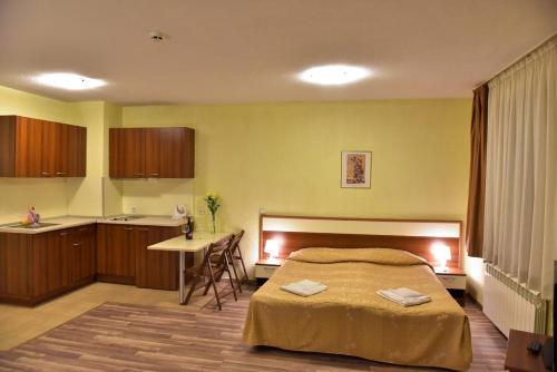 a bedroom with a bed and a table and a kitchen at Apart Hotel Comfort in Bansko
