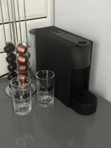 a coffee maker and two glasses on a counter at צימר על הנחל in Qiryat Shemona