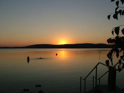 a person standing in the water at sunset at Peace & Beach House in Tihany, Sajkod in Tihany