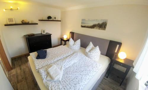 Un dormitorio con una cama con sábanas y almohadas blancas. en Ferienhaus Klönstieg, en Maasholm