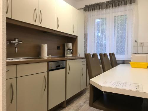 eine Küche mit weißen Schränken sowie einem Tisch und Stühlen in der Unterkunft Ferienwohnung Gartenlaube in Borkum