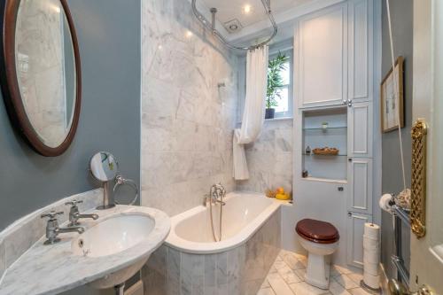 a bathroom with a tub and a sink and a toilet at The Grand "Old Boy" - Marylebone - by Frankie Says in London